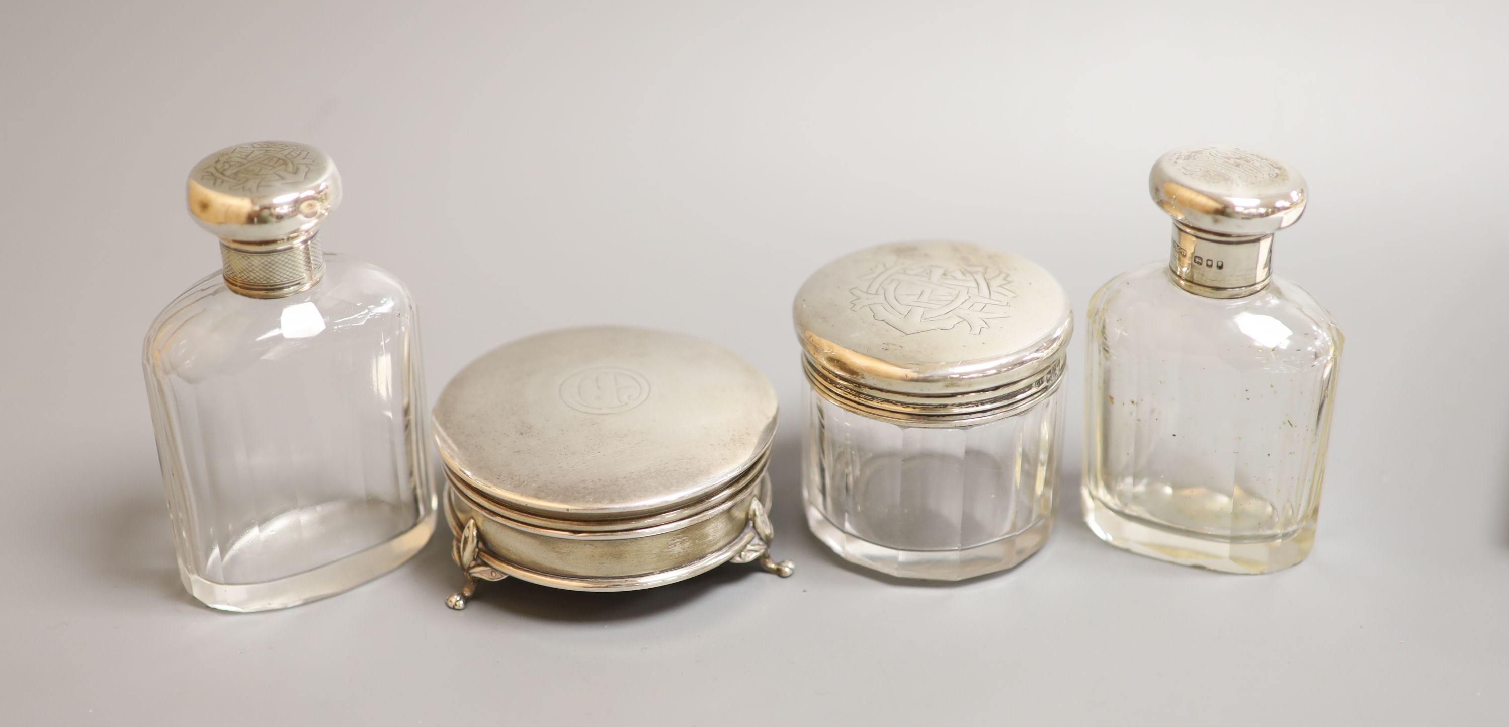 Three silver mounted glass toilet bottles and a George V silver mounted circular trinket box by Mappin & Webb, 77mm.